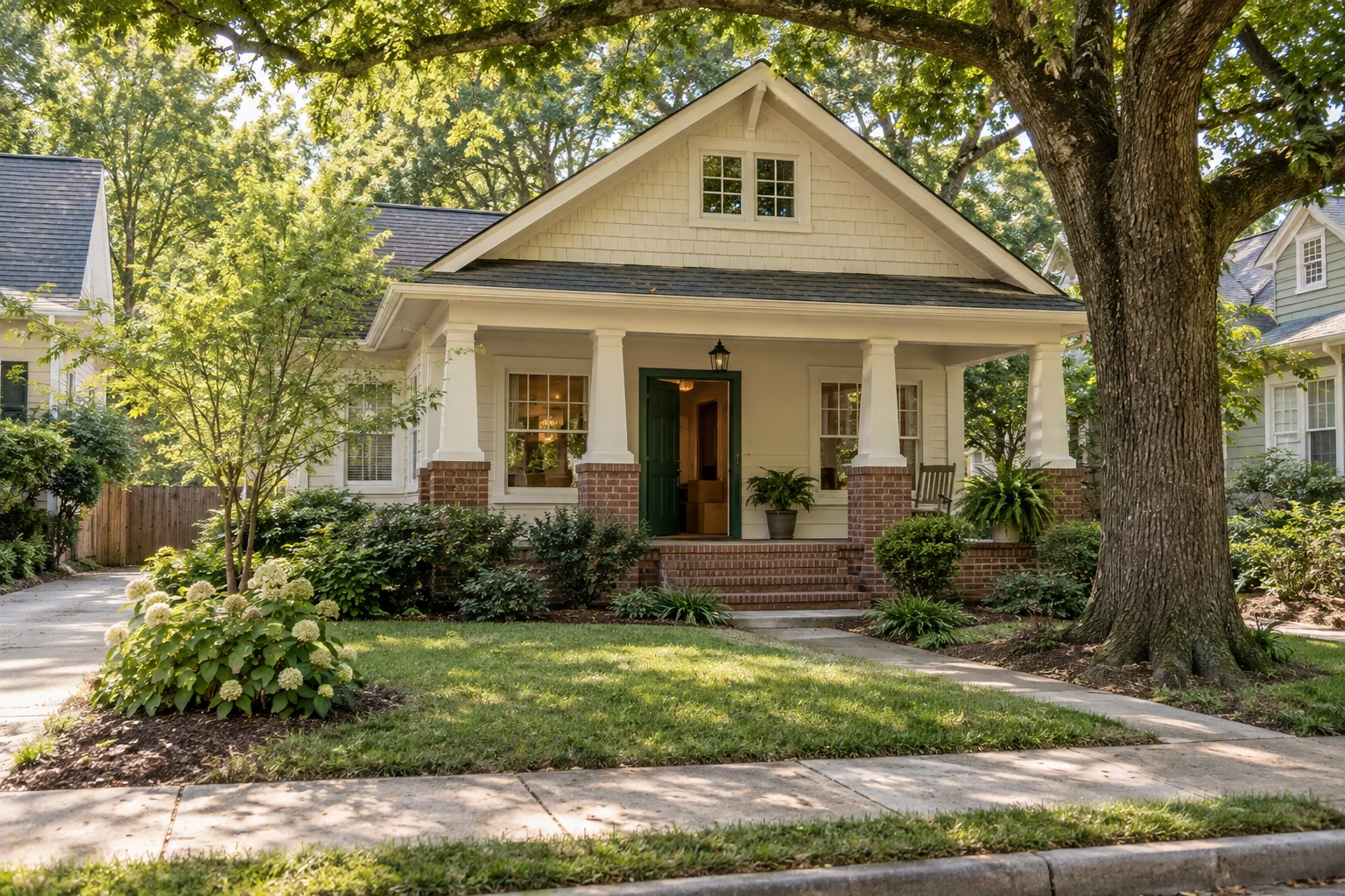 Cream Craftsman bungalow with a green front door and moving boxes inside.