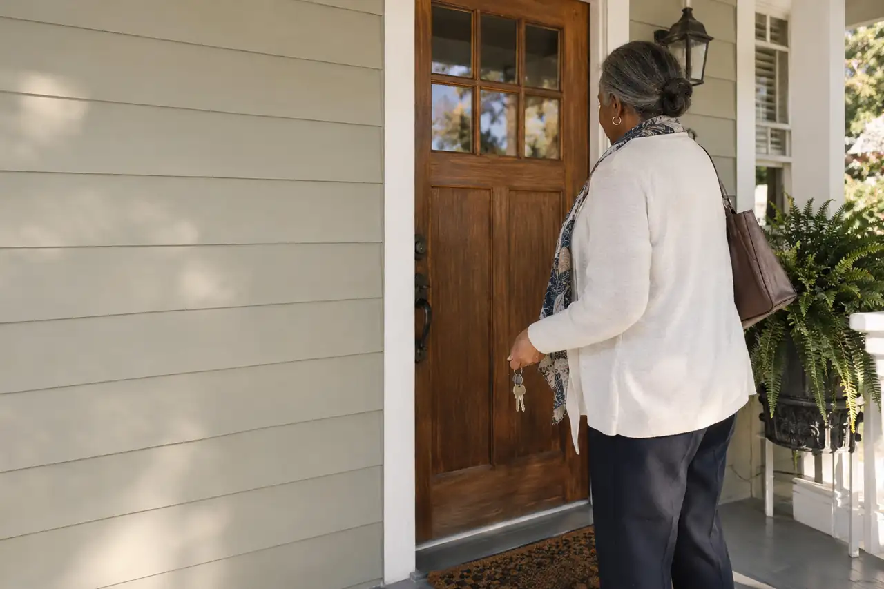 Illustrative scene: a woman in her sixties at the front door of her late mother's Raleigh bungalow holding old keys