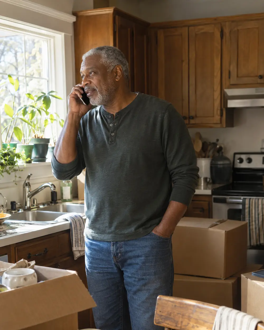 Illustrative scene: a man in his sixties on the phone in his kitchen with a few moving boxes